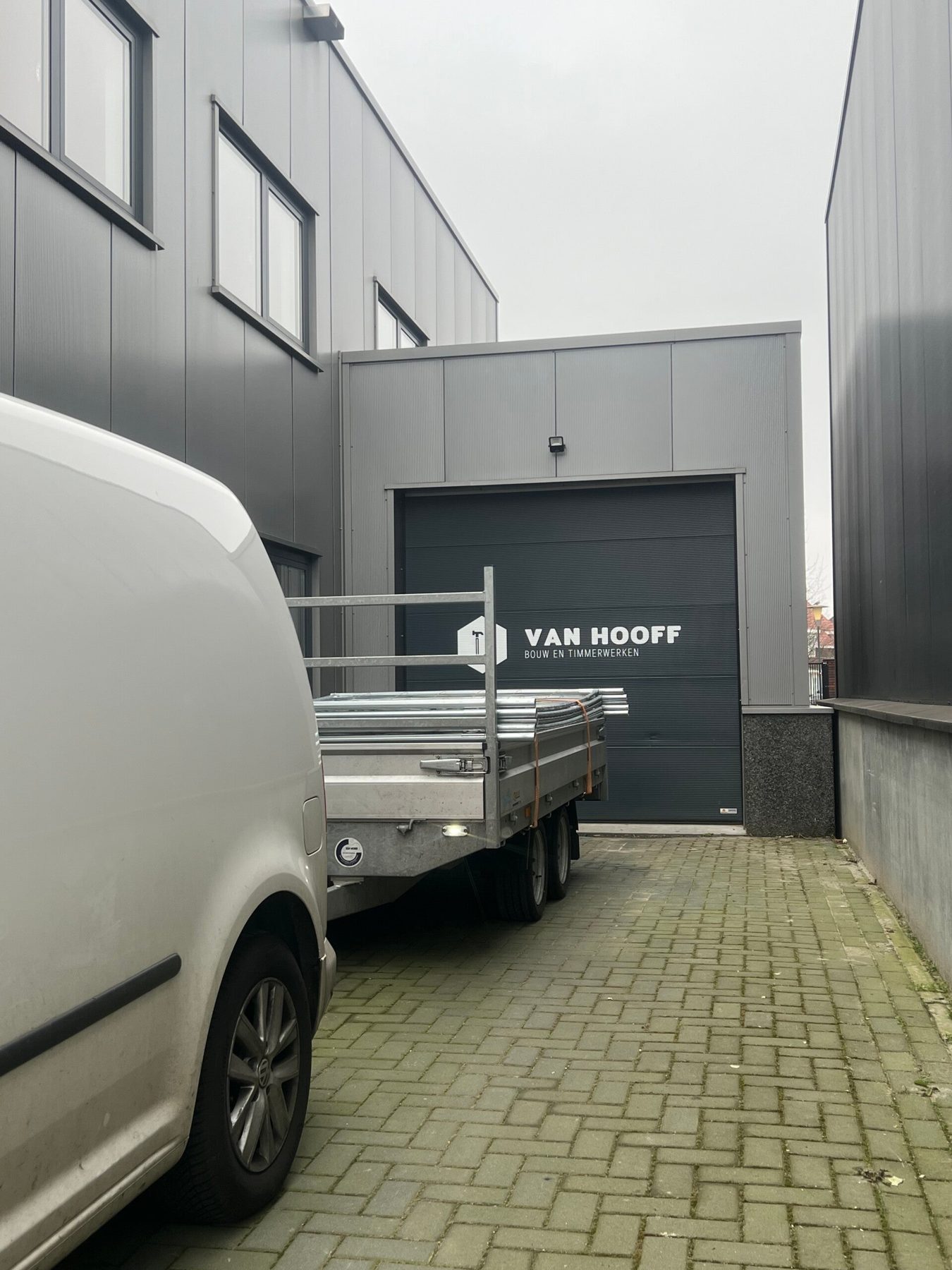 De grijze bedrijfsbus van Van Hooff Bouw en Timmerwerken voor de werkplaats