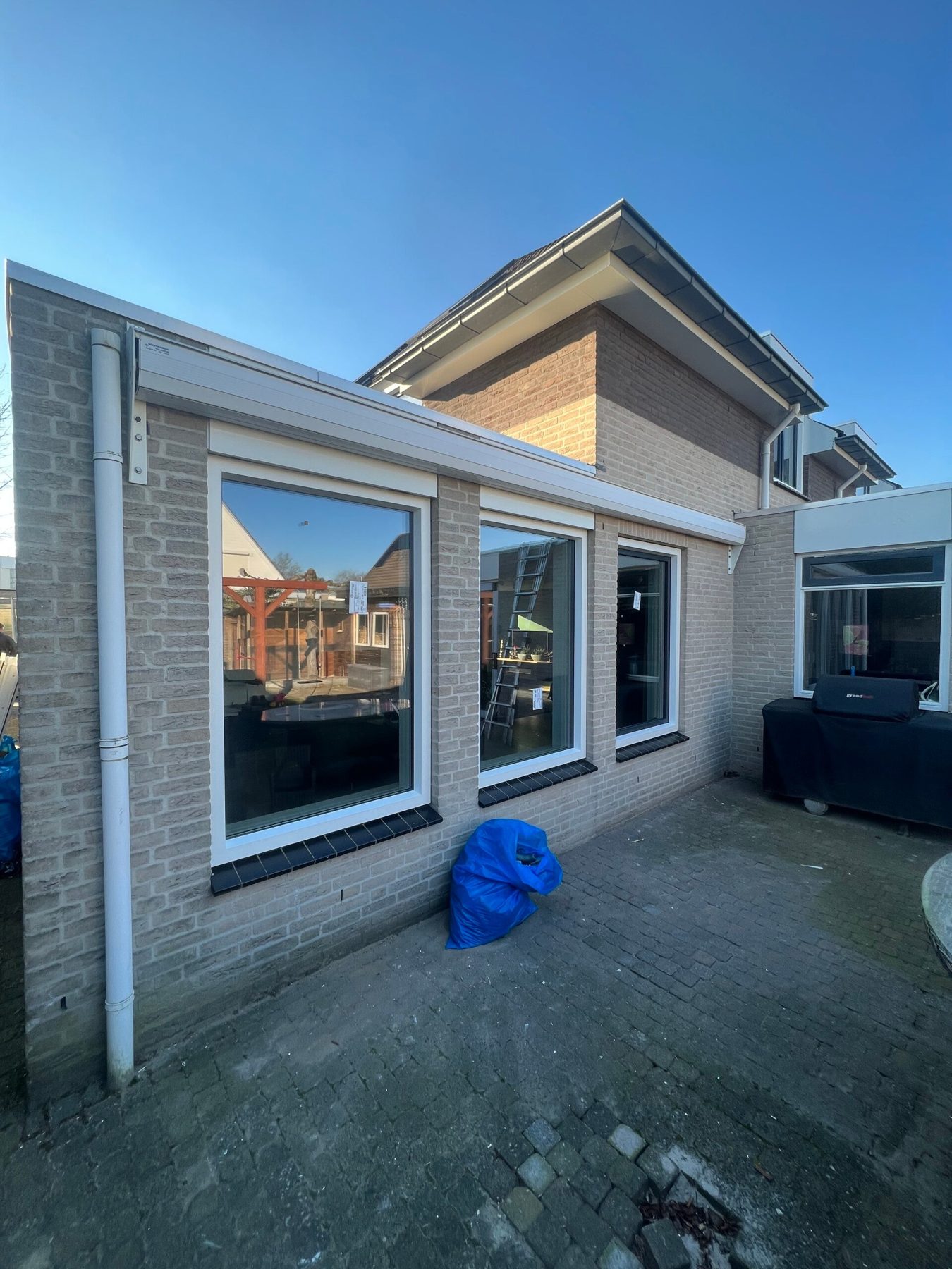 Nieuwe kunststof kozijnen in een gerenoveerde gevel, gezien vanuit de tuin